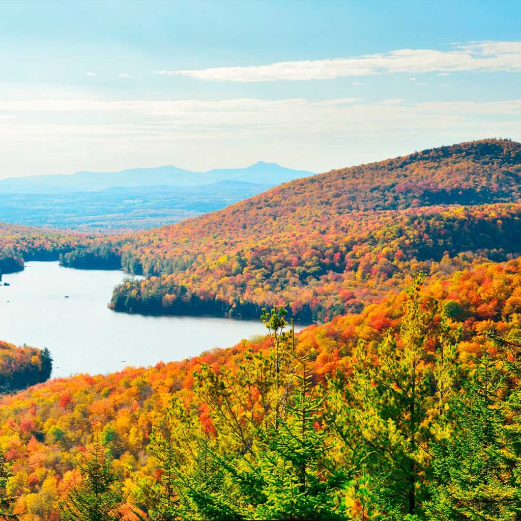 Un lac entouré de montagnes, dans un paysage automnal aux couleurs chaudes et chatoyantes.