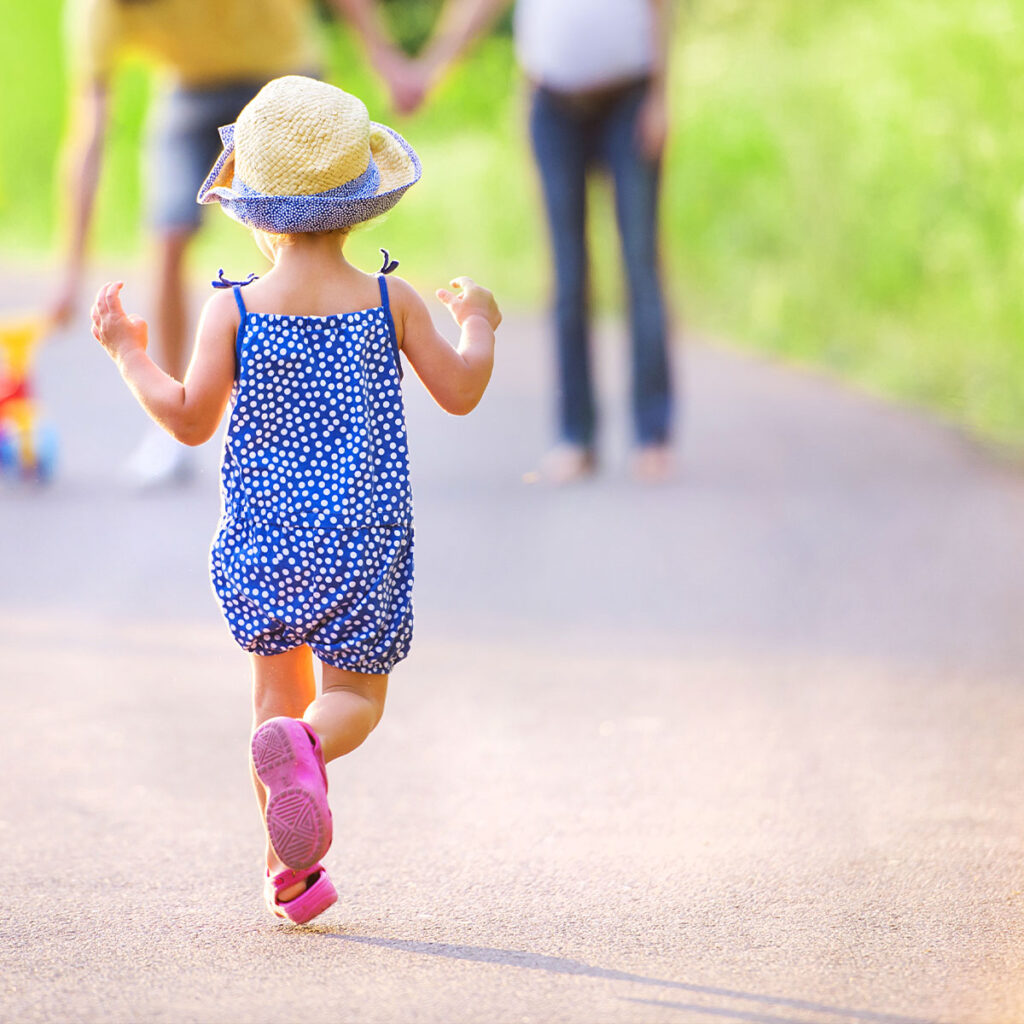 Une jeune fille court vers ses parents, qui l’attendent dans la rue.