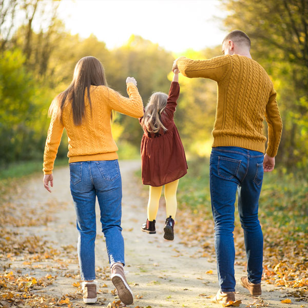 Un couple s'amuse avec leur jeune fille en marchant dans un parc.